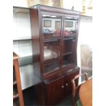 A reproduction glazed bookcase with cupboards under.