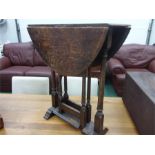 An Edwardian drop leaf table resting on turned supports.