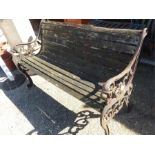 A cast iron garden bench with lions head relief to arms.