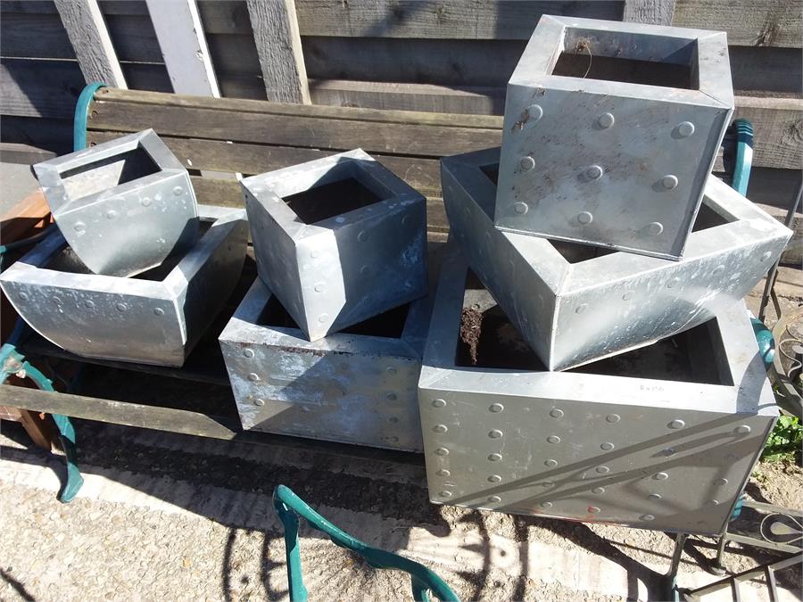 A set of seven various sized metal planters.