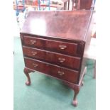 A mahogany three drawer bureau resting on ball and claw feet.