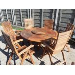 A garden patio set including a teak table with a lazy Susan together with six folding armchairs made