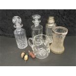 A silver topped glass vase with a silver plated drinking decanter and other glass decanters with