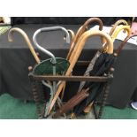 An umbrella stand with various umbrellas and sticks including one plated in 18k gold.