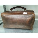 A brown leather Gladstone bag.
