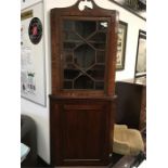 A 19th century mahogany floor standing corner cupboard having a glazed top section with swan neck