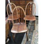 Three Windsor stick back chairs resting on turned legs with a decorative central splat.