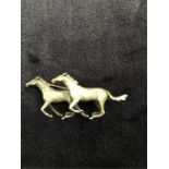 A 9ct gold brooch depicting two running horses (19 grams).