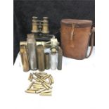 Shell casings with a leather binocular case and old binoculars with a sight scope.