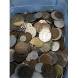 A carton of mixed coins from various countries.
