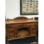 An art nouveau carved front sideboard fitted cupboards drawers and shelves brass handles.