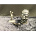 A clay model of a head together with a small cherub statue and one other small statue.