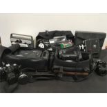 Three vintage video cameras together with a Kodak projector and other camera equipment.