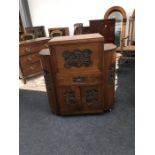 A mid 20th century cabinet with carvings of Oriental scenes to front and curved doors to sides.