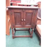 An oak pot cupboard resting on turned supports.