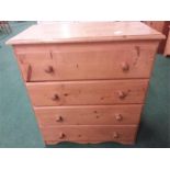 A small pine chest of four drawers resting on a plinth base.