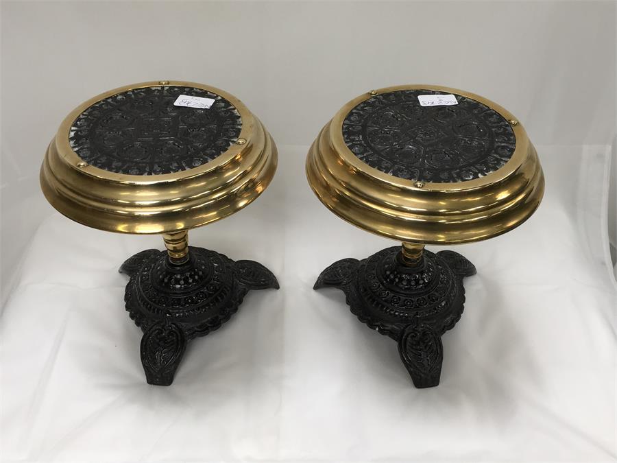 A pair of cast iron and brass kettle stands.