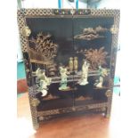 A black lacquered cabinet featuring a Geisha Dance Troupe, with gold painted scenes.