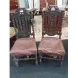 A pair of oak dining chairs decorated with vine and grapes.