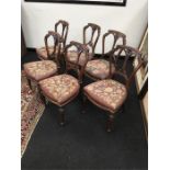 A set of six Victorian walnut dining chairs with carved backs, resting on turned legs, beaded