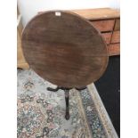 A Victorian circular mahogany tripod table resting on bulbous carved base with brass catch.