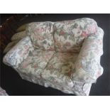 A cottage suite comprising of a two seater and two armchairs with floral linen covers.