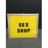An illuminated sign advertising "Sex Shop" with yellow ground and black letters.12" x 10".