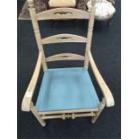 A stripped pine ladder back armchair with turned finials, cross stretcher and turned legs.