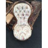 A Victorian shaped back walnut framed occasional chair resting on Spanish legs and covered in