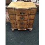 A reproduction bow fronted Walnut chest of four graduated draws resting on bun feet brass handles