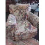 A gentleman's overstuffed armchair with floral covers resting on bun feet.