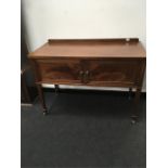 An Edwardian mahogany sideboard with two doors resting on tapered legs with spade feet.