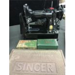 A small Singer electric sewing machine, Model 222K together with accessories including rubber mat,