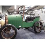 A child's green pressed steel pedal car with plastic parts, spoked wheels and registration '1939'.