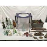 A glass top side table along with vintage bottles and tools.