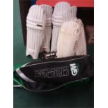 A cricket shoulder bag with various pads and gloves.