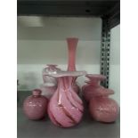 A collection of nine pink glass small vases.