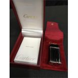 A black enameled Cartier lighter with pouch and box.