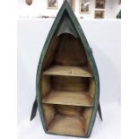 A small wooden bookcase in the shape of a boat, a steel box , an oil on canvas with a print in