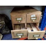 A small four drawer wooden filing cabinet.