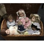 Six modern reproduction porcelain dolls contained in a wicker basket.