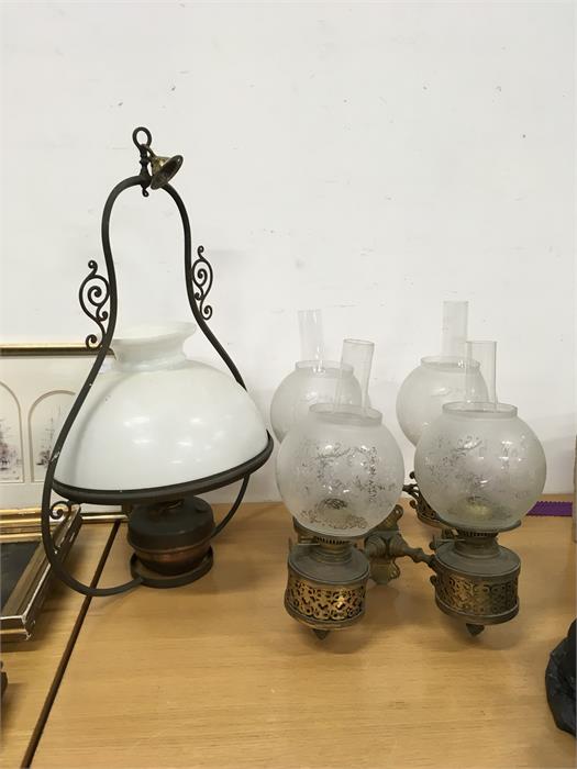 A central hanging oil lamp with white glass shade together with a pair of wall oil lights