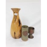 A large yellow and black pottery vase together with two brown pottery vases.