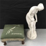 A plaster figurine with a foot stool.