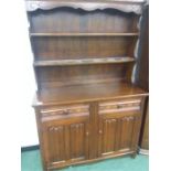 An oak dresser with linen fold to cupboard doors with two shelved plate rack above.