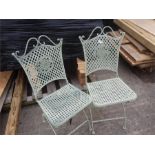 A pair of metal folding lattice chairs.