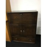 An Ercol dark wood cabinet with top section and cupboards and drawer under.