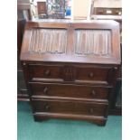 An oak four drawer bureau with linen fold pattern.