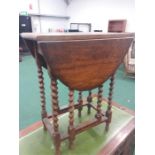 A small oak drop leaf table resting on barley twist supports.