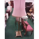 A brass standard lamp with pink fabric shade.